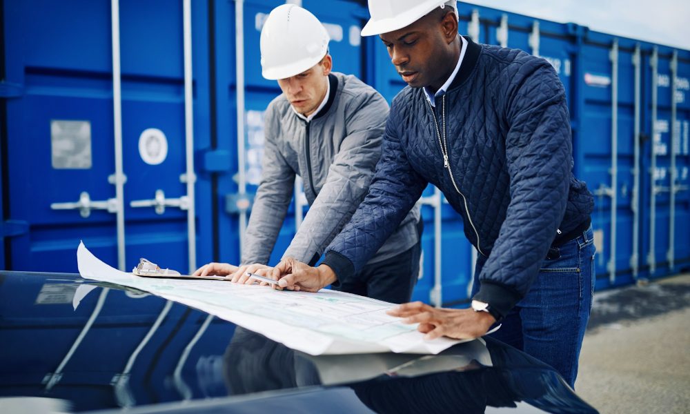 Two engineers discussing building plans together in a freight yard
