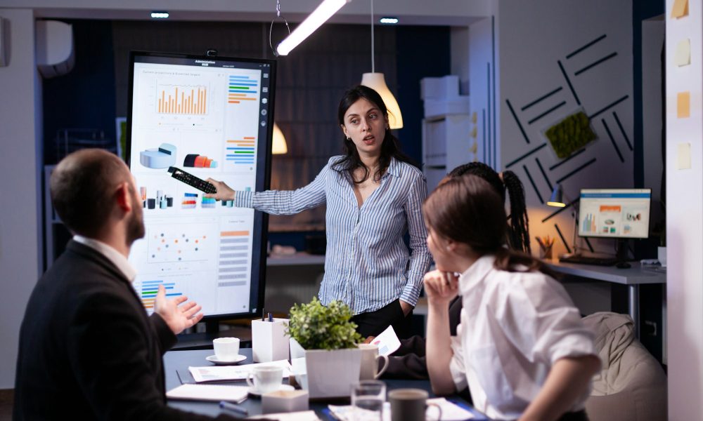 Workaholic focused businesswoman explaining management solution pointing strategy on monitor